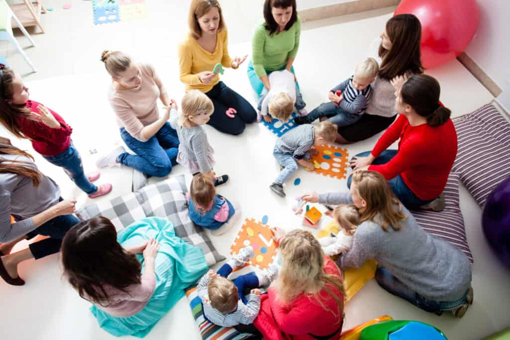 Children with mothers sit in a circle and study colors, numbers and figures in the kindergarten